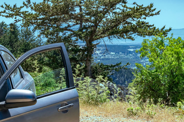 A car with an open door stands on a hill or top of a mountain with view on valley. Summer Landscape Background
