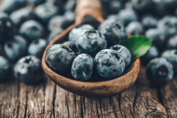 Blueberries in wooden spoon on old wood background. Healthy eating and nutrition concept.
