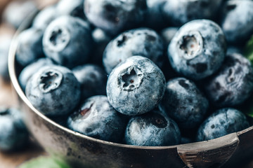 Freshly picked blueberries in bowl on wooden background. Healthy eating and nutrition.