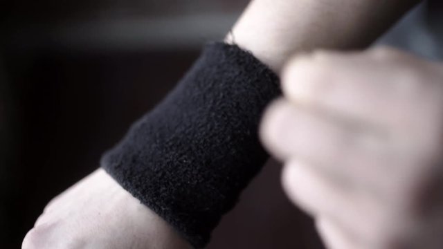 Athlete wears black wristbands. Action. Closeup of athlete adjusts his wristbands on his hands, not to hurt wrist during sports