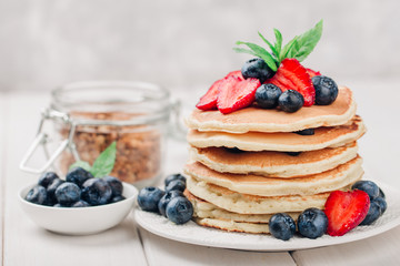 Classic american pancakes with fresh berry on white wood background. Summer homemade breakfast.
