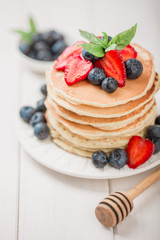 Classic american pancakes with fresh berry on white wood background. Summer homemade breakfast.