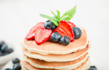 Classic american pancakes with fresh berry on white wood background. Summer homemade breakfast.