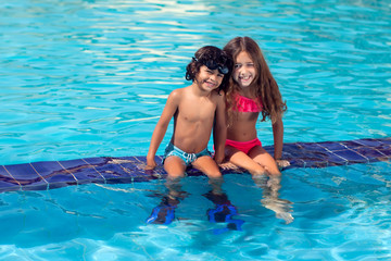 Little boy and girl play in the swimming pool. Children and summer concept
