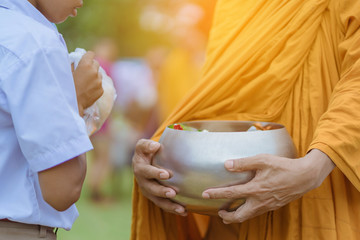 Teachers and students together make merit to give food offerings to a Buddhist monk on important...