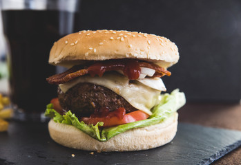 Delicious burgers with beef patty, bacon, cheese and cabbage and a soda