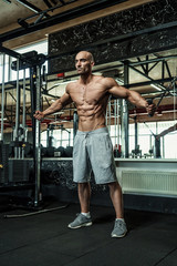 Young handsome athlete, bodybuilder, weightlifter with a perfect body, working out in the gym,...