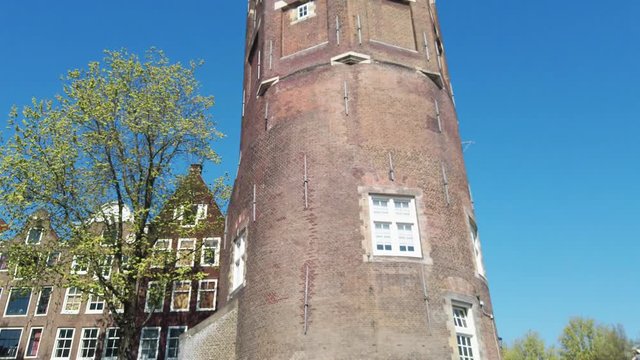 Montelbaanstoren tower on Oudeschans canal. View from boat trip in sunny day
