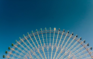 Large ferris wheel against a blue sky with sunlight glinting off the colourful wheel.