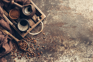 Coffee on wooden tray with coffee beans on dark textured background. Top view with copy space. Background with free text space.