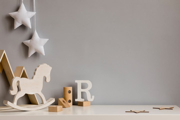 Stylish and cozy childroom with  wooden mountain box, horse, blocks and hanging white stars on the...