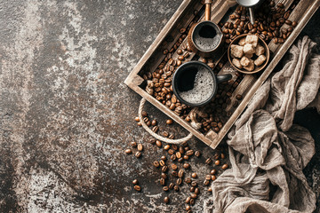 Coffee on wooden tray with coffee beans on dark textured background. Top view with copy space. Background with free text space.