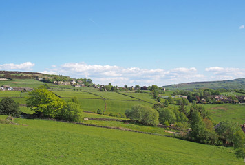 Fototapeta na wymiar iew of the village of midgley in west yorkshire with surrounding green fields and farmhouses and moors in a spring pennine landscape
