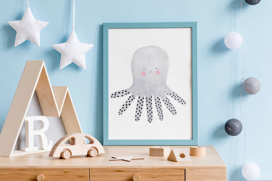 The modern scandinavian newborn baby room with mock up poster frame, wooden toys, mountain box and children accessories. Minimalistic and cozy interior with blue walls. Haniging cotton balls and stars