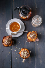 Muffin with milk chocolate and nuts, flavored orange tea on wooden background top view