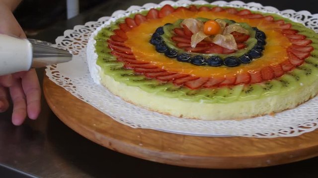 Il pasticcere finisce di decorare la torta di frutta con la panna