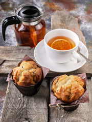 Homemade vanilla Muffins and flavored tea on a rustic wooden background. Close-up. Vertical shot