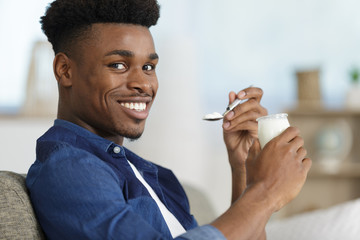 smiling young man eating yogurt