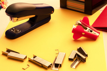 stapler, paper clips, anti-stapler on the desktop on the background of stickers and folder in...