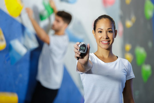 woman wall climbing trainer holding chronometer
