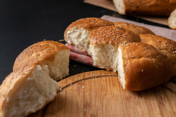freshly baked  soft sweet divided bun with sesame seeds on it, torn off piece of breads