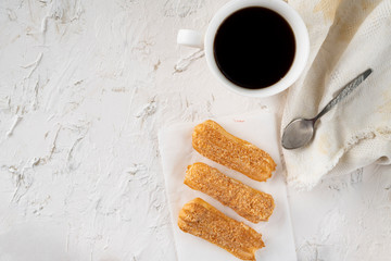 morning snack with coffee and creamy eclair on a table with white tablecloth, business breakfasts