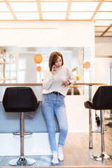 Young happy woman talking on mobile phone in the kitchen