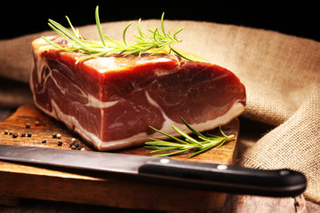 Italian prosciutto crudo or jamon with rosemary. Raw ham on wooden board