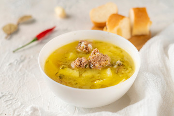 hot fresh boiled soup with meatballs and potato with bread on a white table, tasty dinners