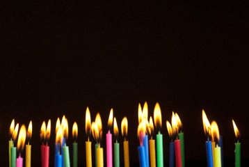 Colorful candles burning in the dark. Flames in darkness.