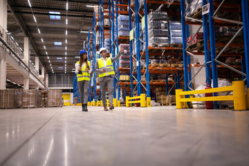 Warehouse managers walking in a large storage department controlling distribution to the market.