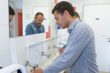 Fototapeta premium man washing hands in bathroom washbasin