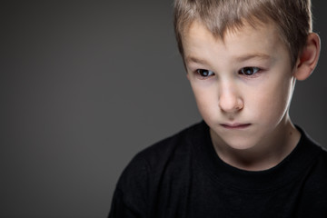Grief-stricken little boy - feeling intense sorrow, remorse, sadnesss - studio portrait - vivid...