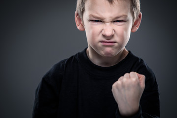 Naklejka premium Loads of aggression in a little boy - education concept hinting behavioral problems in young children (shallow DOF) - little boy with hands clenched into fists about to punch someone