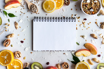 Healthy food nutrition concept, fresh summer fruits nuts granola seeds and empty blank notebook on...