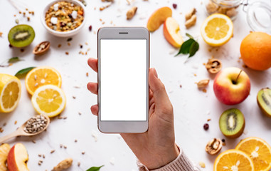 Female hands holding smartphone on healthy food background, woman using phone search mobile apps...
