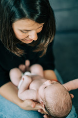 New mother sleeping her cute adorable newborn on her arms. Baby expresses calm and peace. Family, new life, childhood, beginning concept.