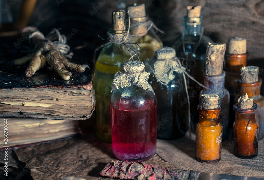 Wall mural a witchery stuff: multiple tincture bottles, bunches of dry healthy herbs, stack of ancient ritual b