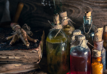 A witchery stuff: multiple tincture bottles, bunches of dry healthy herbs, stack of ancient ritual books, amulets, candles, chicken feet, sack of medicinal and magical herbs. 