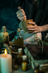 Dark Witch at work: black magic woman makes the witchery by mixing herbs, casting the spells, running magic rituals