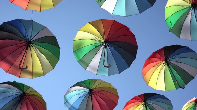 Street installation of multi-colored open umbrellas. The sky of colorful umbrellas. Background colorful urban umbrella street decoration.	