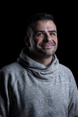 Fototapeta premium Studio portrait of a smiling man looking at the camera. Isolated on black background. Vertical.