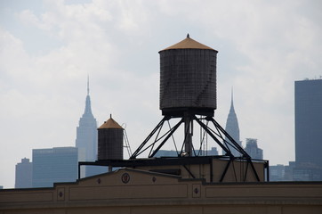 water tower on a roof in Queens, New York City, empire state and chrysler building  background