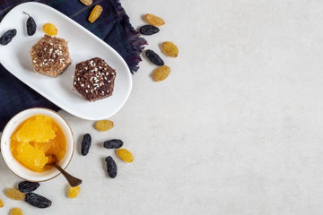 Healthy sweets made from natural ingredients on a white plate. Near honey, yellow and dark blue raisins