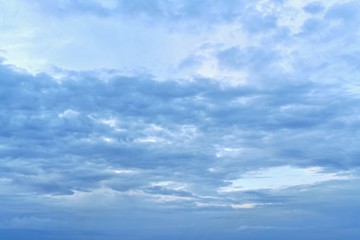 Blue sky with dark blue clouds. Above, above the clouds, the bright area on the left. Below are more elongated clouds, horizontally more crowded in the center.