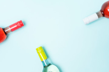 Layout frame of foil caps in different bright colors of white and rose wine bottles on blue background with copy space. Minimal abstract colorful mockup concept of alcohol beverage. Flat lay.