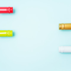 Screw bottle foil caps in different bright colors of white and rose wine bottles on blue background with copy space. Minimal abstract colorful mockup concept of alcohol beverage. Flat lay.