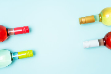 Mockup frame of bottle foil caps in different bright colors of white and rose wine bottles on blue background with copy space. Minimal abstract colorful mockup concept of alcohol beverage. Flat lay.