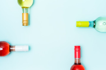 Mockup frame of bottle foil caps in different bright colors of white and rose wine bottles on blue background with copy space. Minimal abstract colorful mockup concept of alcohol beverage. Flat lay.