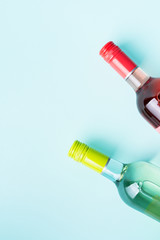 Screw bottle foil caps in different bright colors of white and rose wine bottles on blue background with copy space. Minimal abstract colorful mockup concept of alcohol beverage. Flat lay.